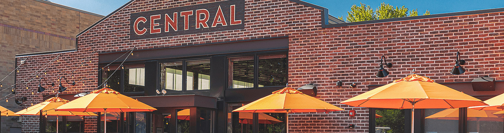 Several orange Frankford Market Umbrellas being used in front of a restaurant