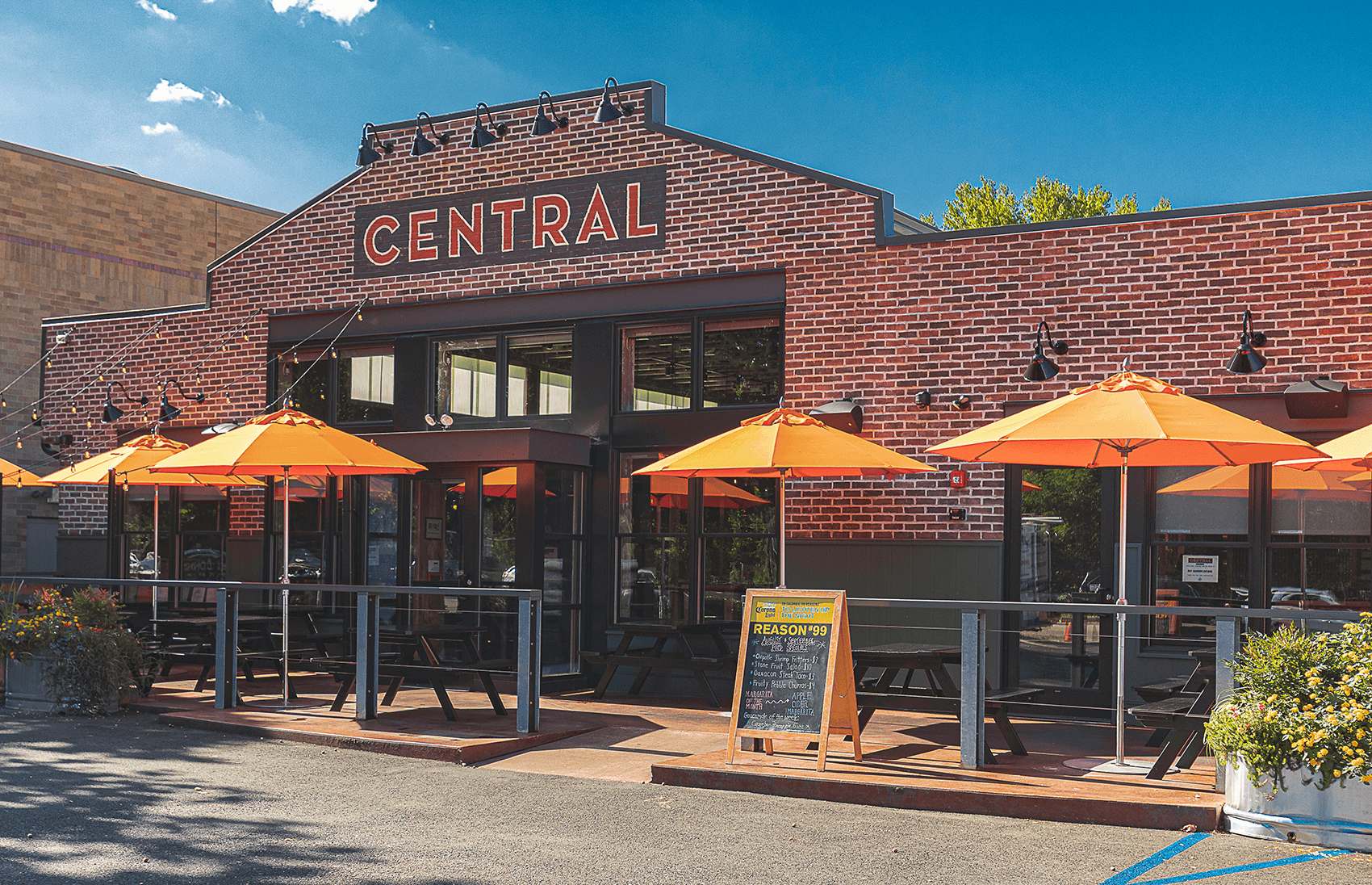 Several orange Frankford Market Umbrellas being used in front of a restaurant