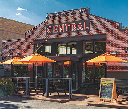 Orange Octagon Frankford Auto Tilt Monterey Umbrellas shading the outside of a restaurant's dining area and entrance