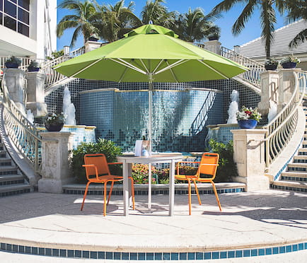 Green Frankford Greenwich Market Umbrella with table and chairs, used in a hospitality setting