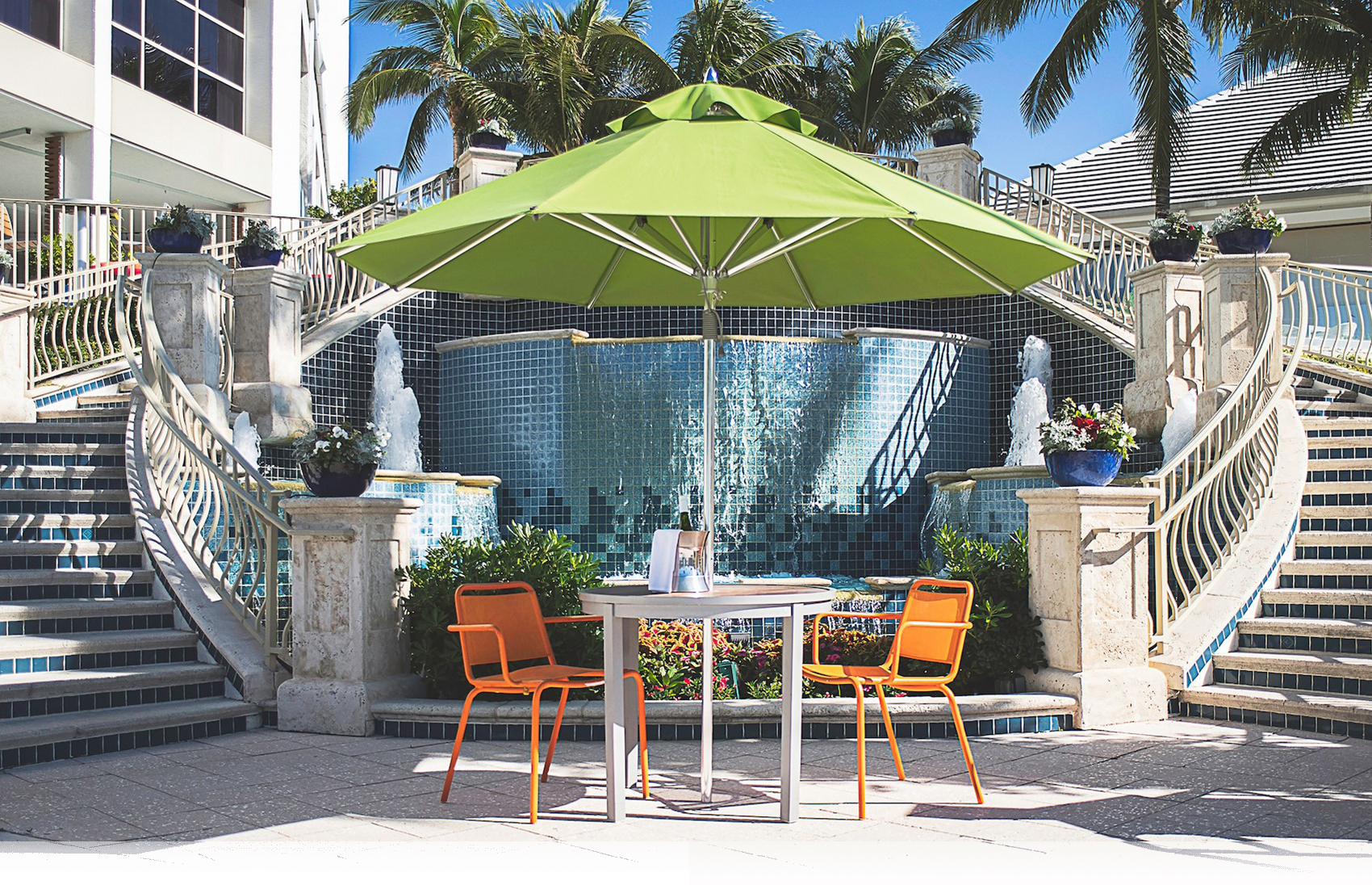 Green Frankford Greenwich Market Umbrella with table and chairs, used in a hospitality setting